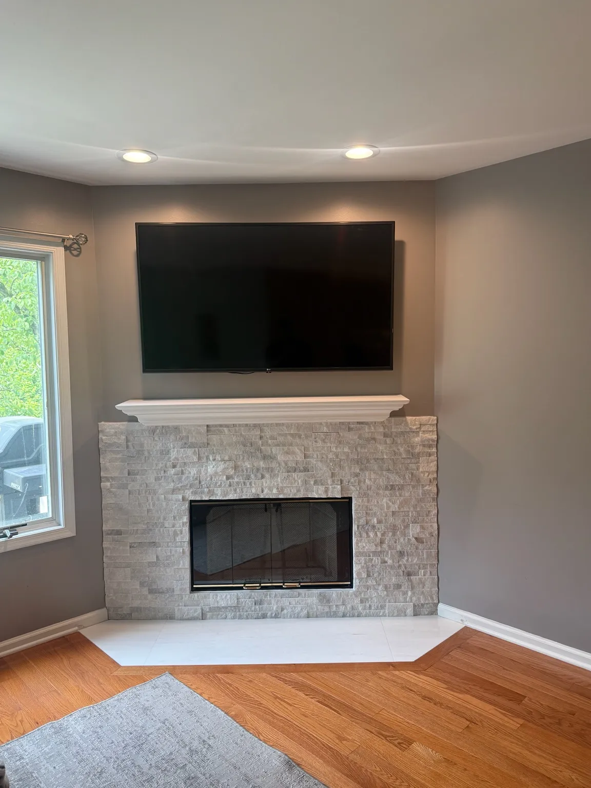 Corner fireplace with a light stacked-stone surround and a white painted mantel.