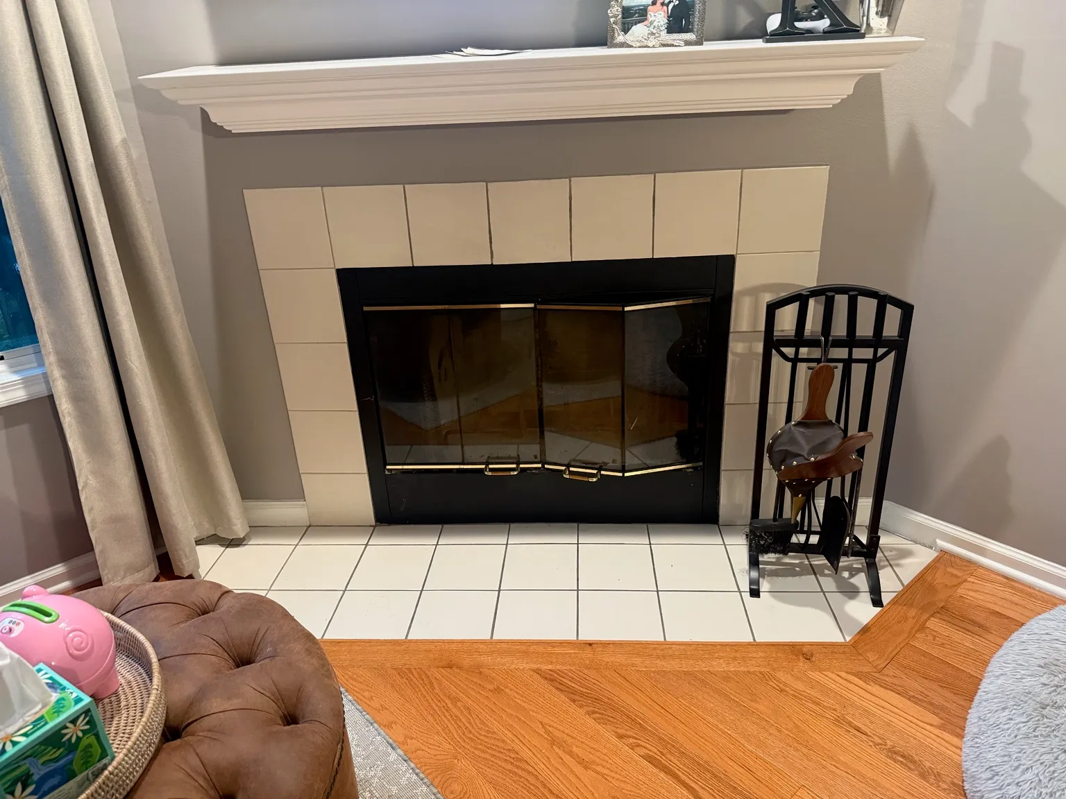 Fireplace with a cream tile surround and white painted mantel, fitted with black-framed glass doors over a white tile hearth.